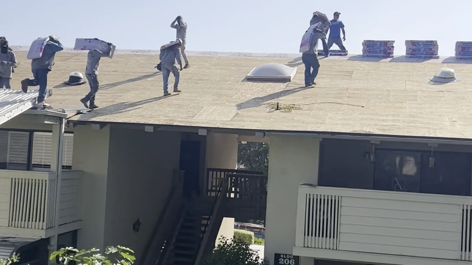 Pacific Roofing installer fitting new rain gutters along a roof eave