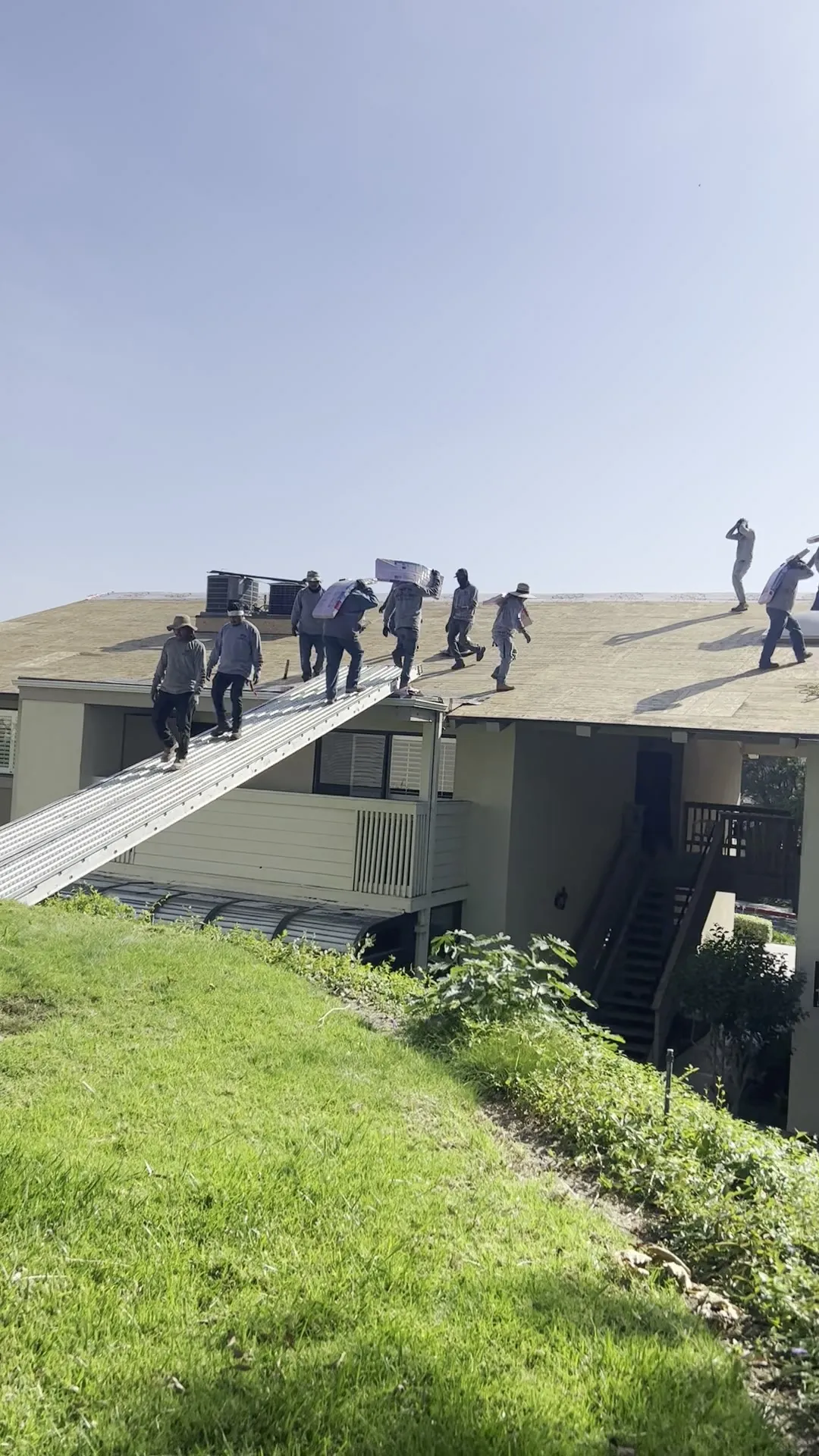Pacific Roofing crew carrying materials up to a roof