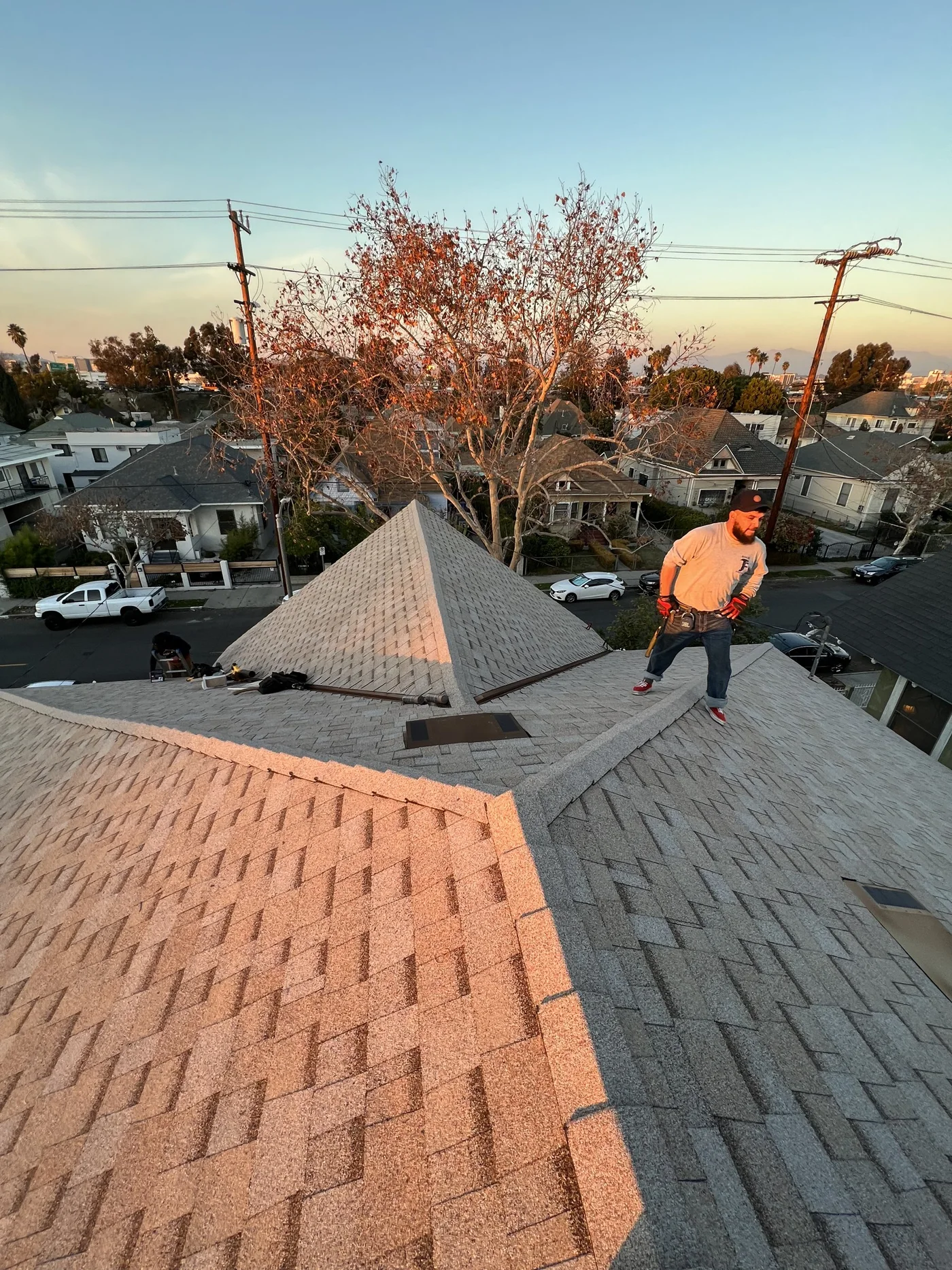 A Pacific Roofing crew finishing a roof at golden hour